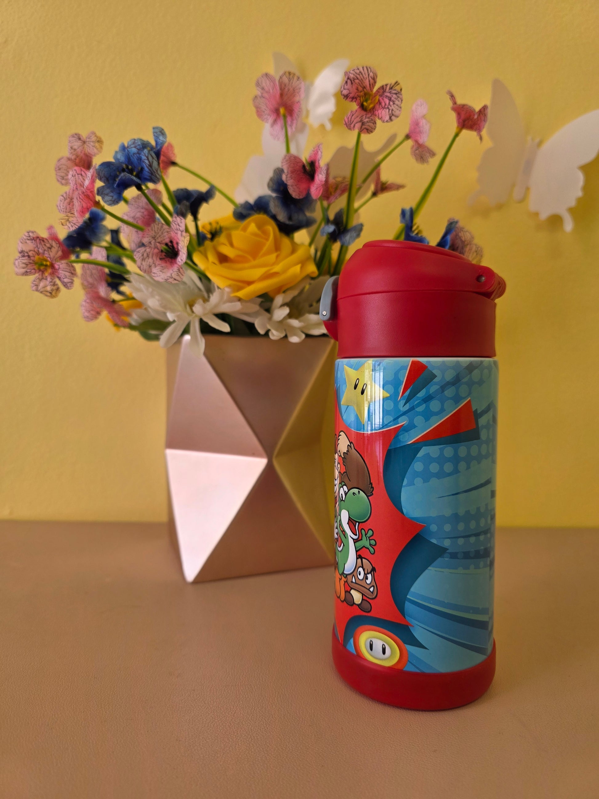 Colorful children's thermos with cartoon design on a yellow background