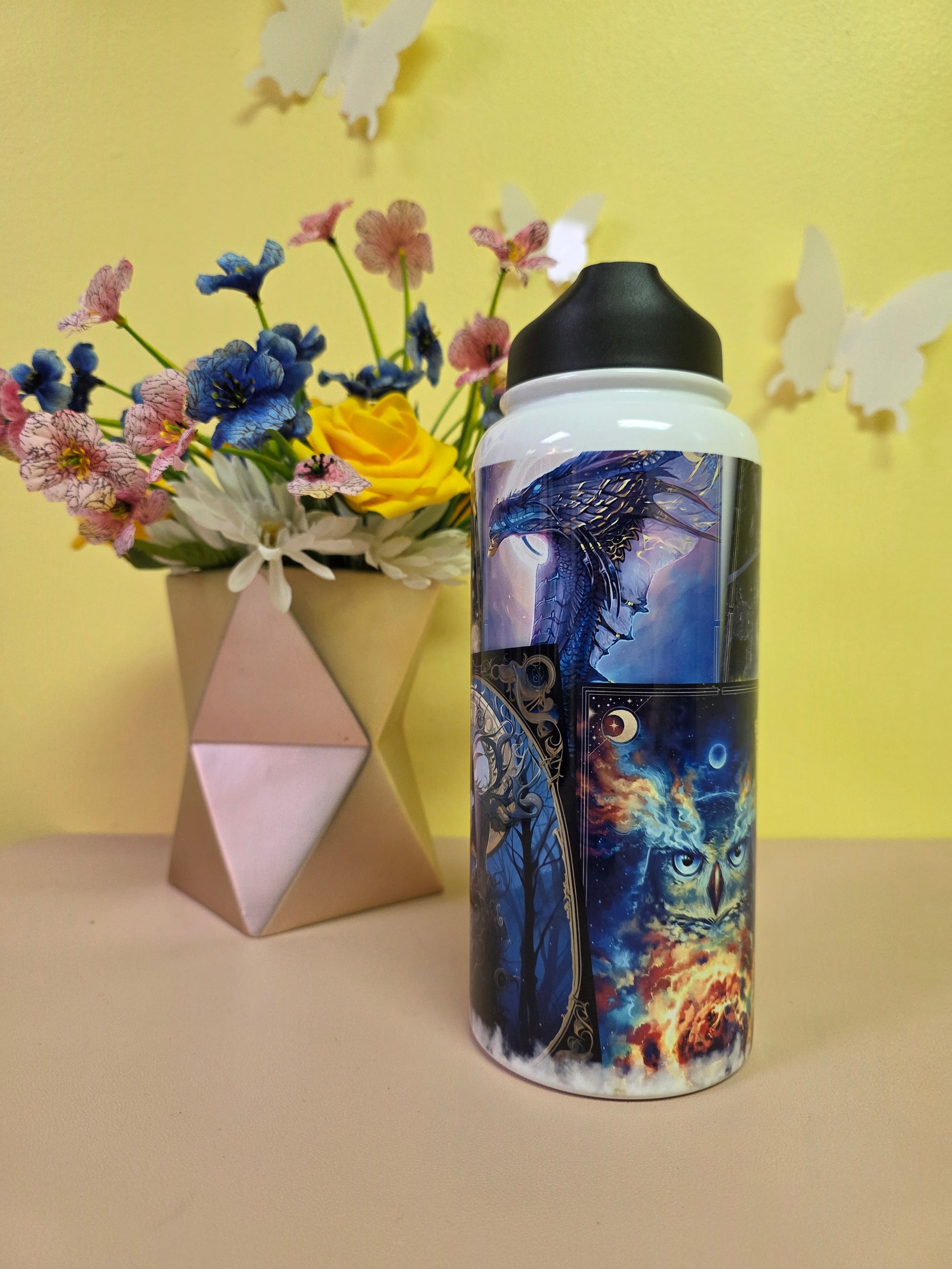 Colorful water bottle with artistic design on a yellow background with flowers and a box.