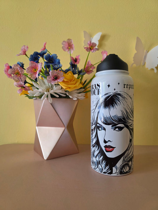 Taylor Swift themed water bottle tumbler on a table with a yellow background