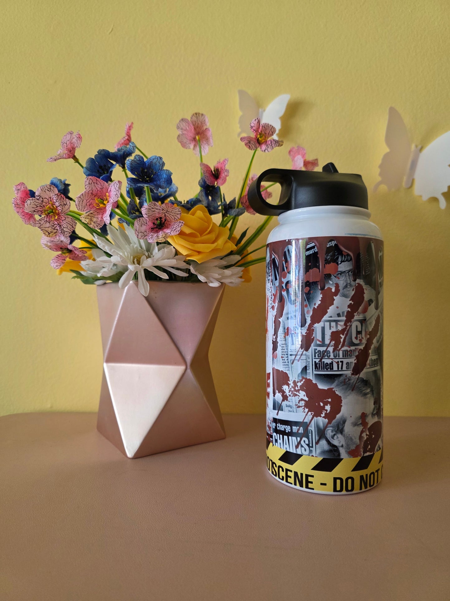 True Crime themed water bottle tumbler on a table with yellow background