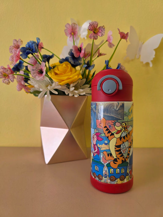 Winnie the Pooh tumbler on a table with flowers in the background. 